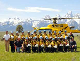 Photo of Teton Interagency Helitack crew with helicopter and Tetons in background