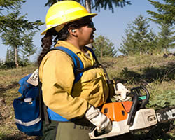 female American Indian Firefighter holding a chainsaw