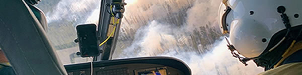 person in a helicopter over a wildland fire