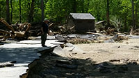 (image) Campground loop with pavement crumped and litered with debris and restroom in the background