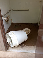 (image) Restroom damaged and covered with mud and debris.